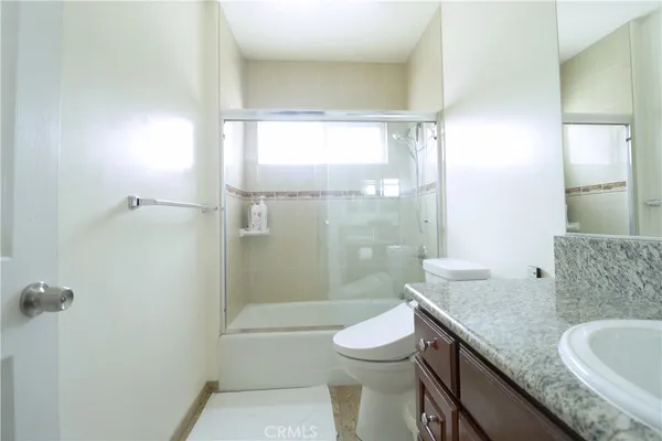 a bathroom with a granite countertop sink a toilet and shower