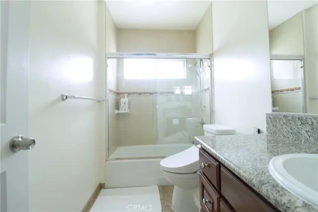 a bathroom with a granite countertop sink a toilet and shower