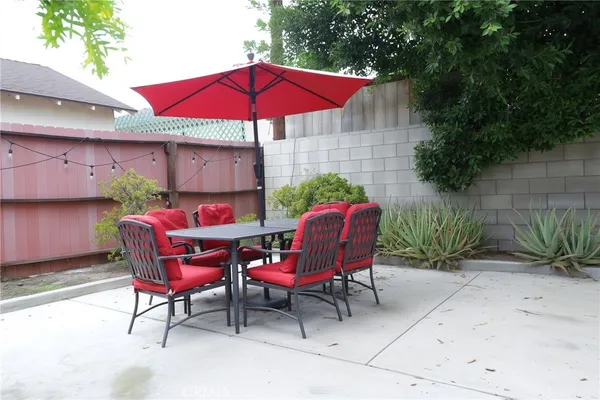 a patio with tables and chairs under an umbrella
