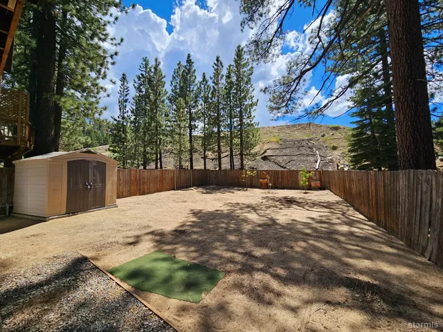 a backyard of a house with trees and wooden fence