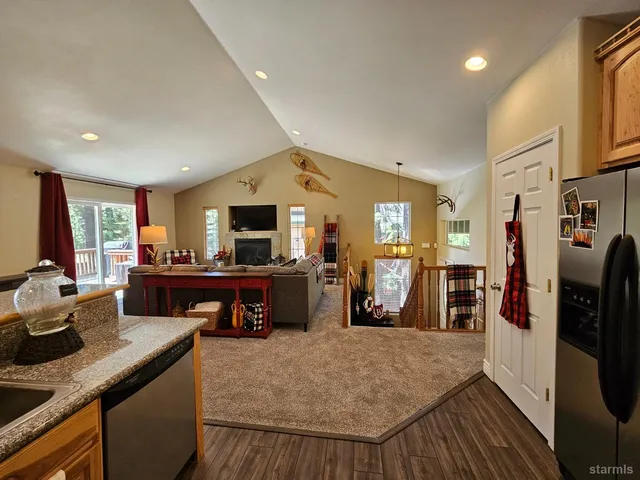 a kitchen with stainless steel appliances granite countertop sink stove refrigerator and wooden floor