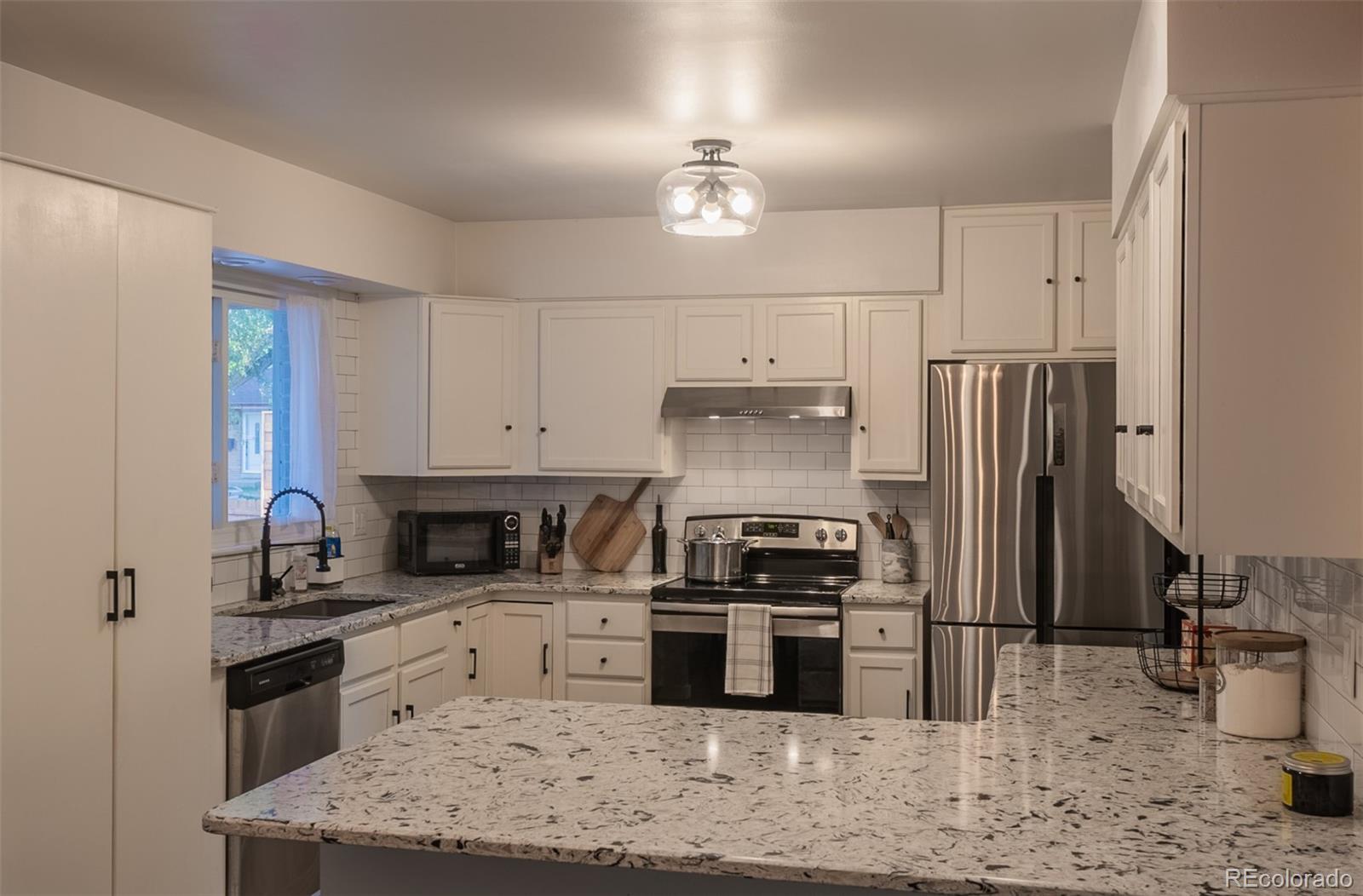 4947 South Perry Street Littleton, CO 80123 - Photo 5 of 24 a kitchen with stainless steel appliances granite countertop a sink stove and refrigerator