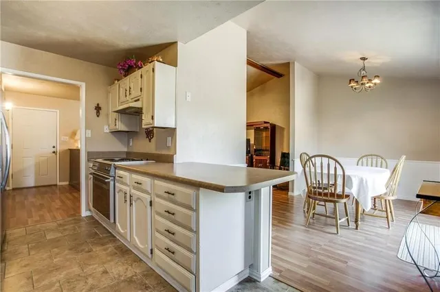 a kitchen with stainless steel appliances kitchen island granite countertop a table chairs and a refrigerator