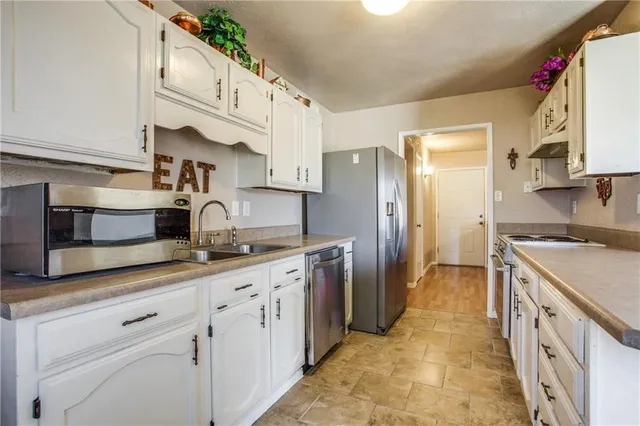 a kitchen with granite countertop a sink stove refrigerator and cabinets