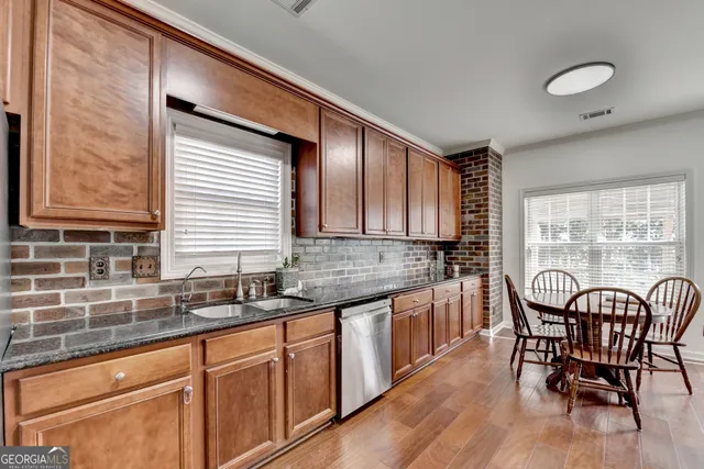 a kitchen with granite countertop a sink cabinets and stainless steel appliances
