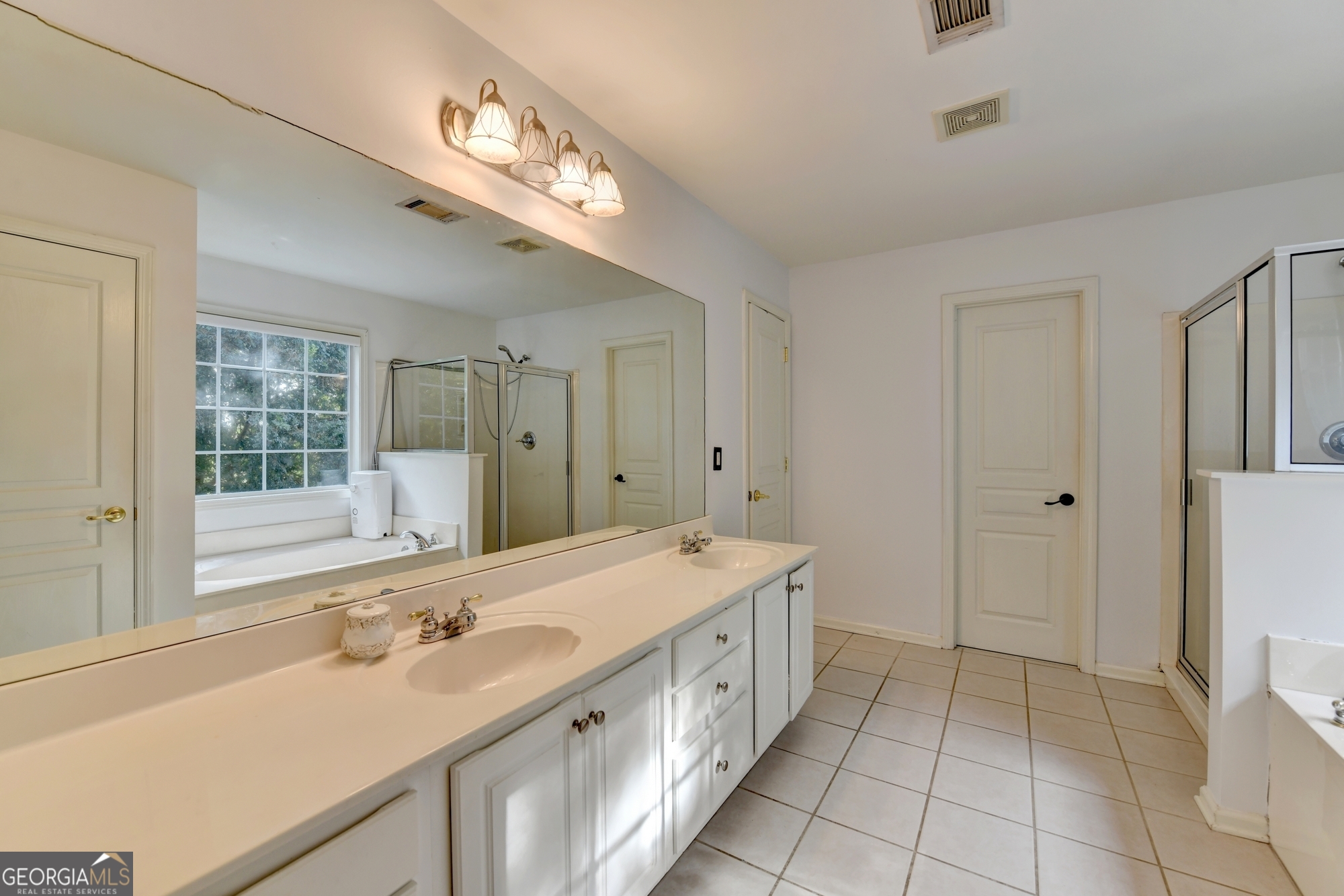 952 Cambron Cmns Trace Suwanee, GA 30024 - Photo 33 of 69 a spacious bathroom with a double vanity sink a mirror and a bathtub