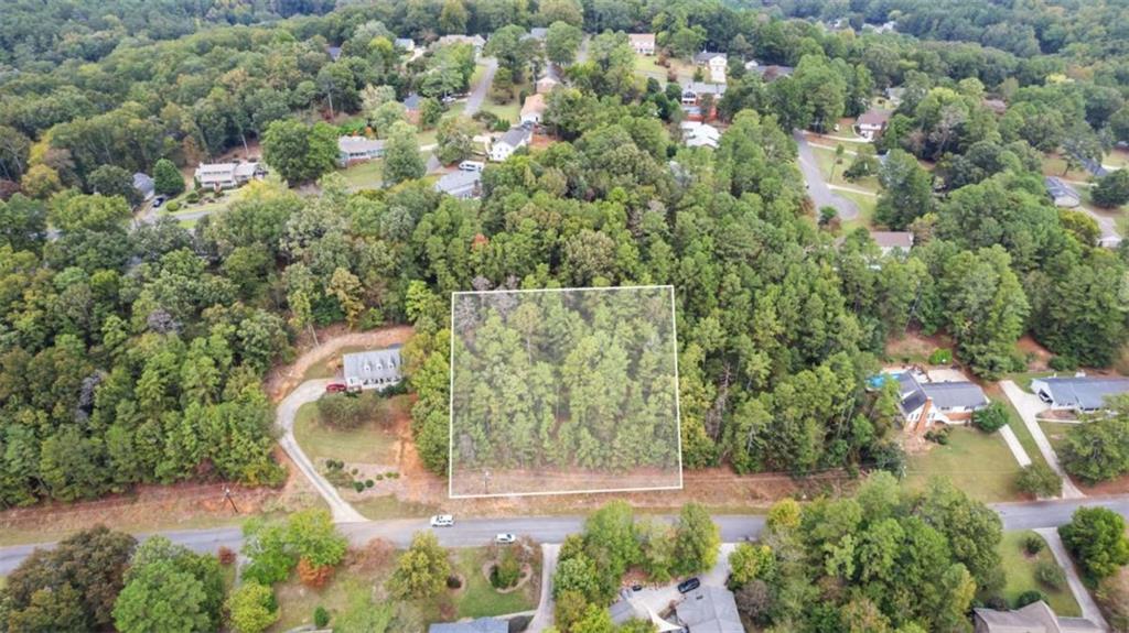 an aerial view of a residential houses with yard and greenery