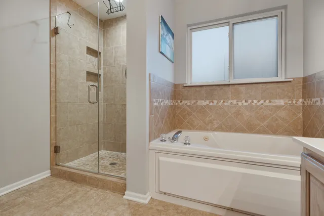 a bathroom with a tub a mirror and a shower