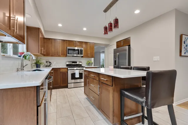 a kitchen with stainless steel appliances granite countertop a table chairs sink and cabinets