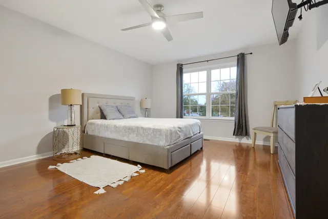 a bedroom with a bed dresser and a large window