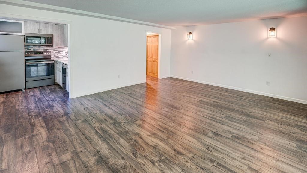 376 Great Road, Unit 15 Acton, MA 01720 - Photo 15 of 27 an empty room with wooden floor kitchen view and windows