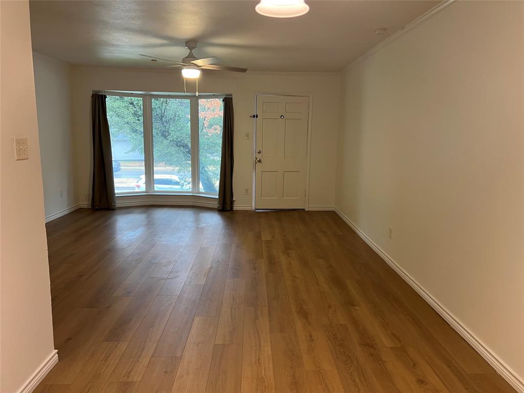 3929 Inwood Road, Unit 2021 Dallas, TX 75209 - Photo 5 of 24 Wood-finish flooring, white walls, decorative ceiling fan, multi-pane bay window, and a paneled entry door