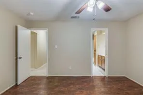 an empty room with wooden floor cabinet and windows