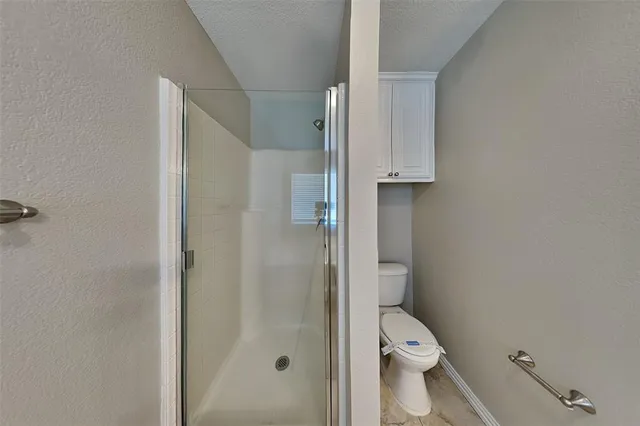 a bathroom with a granite countertop toilet and a shower