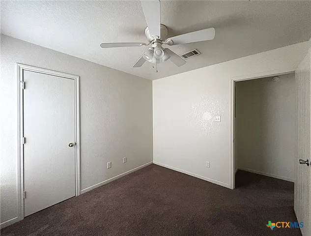 an empty room with a ceiling fan and a window