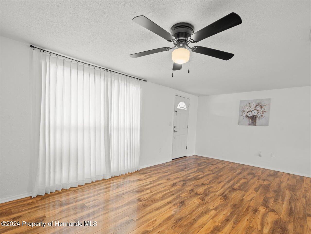 3902 Glissade Drive New Port Richey, FL 34652 - Photo 11 of 39 a view of a big room with wooden floor and windows in a room