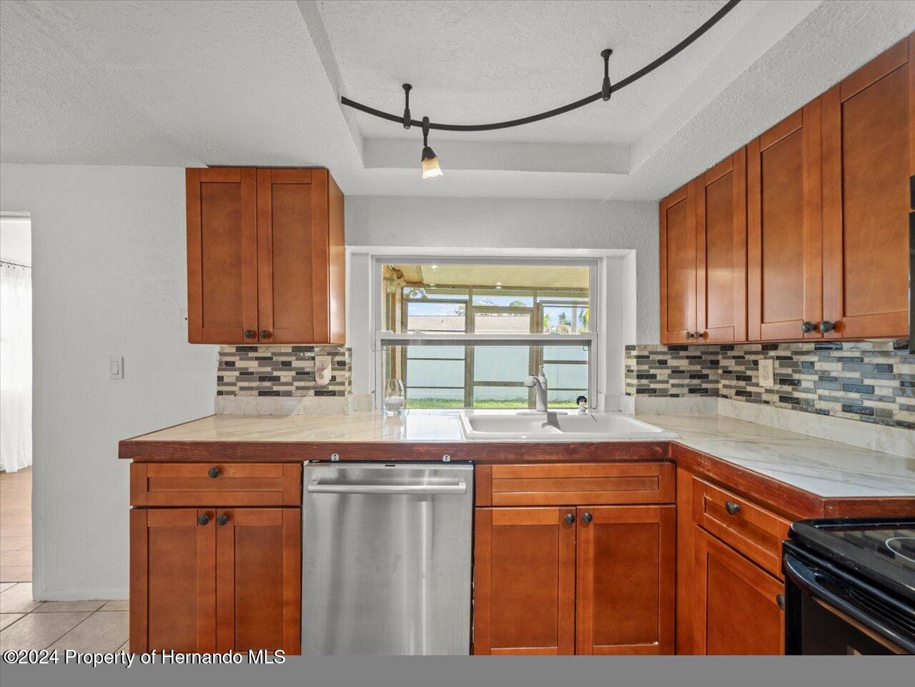 3902 Glissade Drive New Port Richey, FL 34652 - Photo 19 of 39 a kitchen with stainless steel appliances granite countertop wooden cabinets and a counter top space