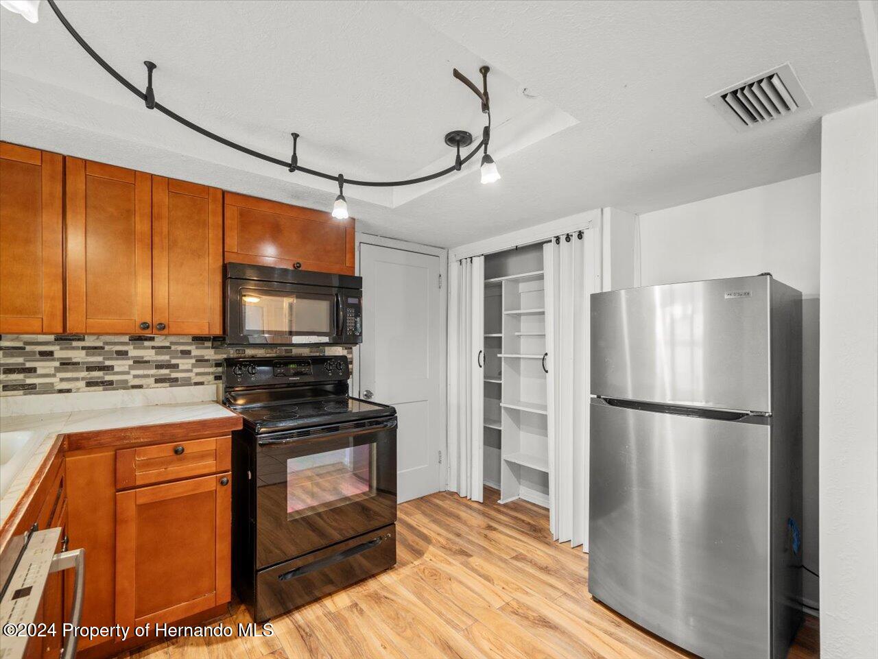 3902 Glissade Drive New Port Richey, FL 34652 - Photo 22 of 39 a kitchen with stainless steel appliances granite countertop a refrigerator a stove and a sink with wooden floor