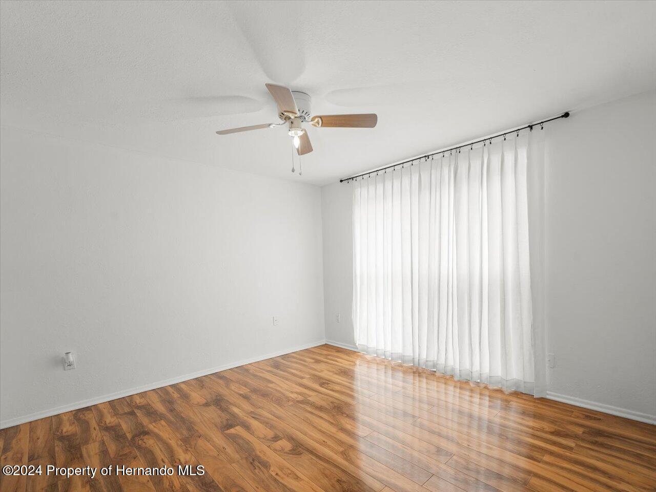 3902 Glissade Drive New Port Richey, FL 34652 - Photo 28 of 39 an empty room with wooden floor fan and windows