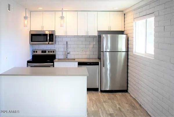 a kitchen with a refrigerator a microwave a stove and a window