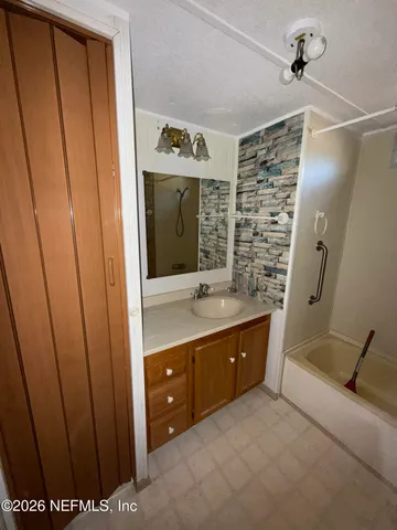 a bathroom with a sink and mirror with shower