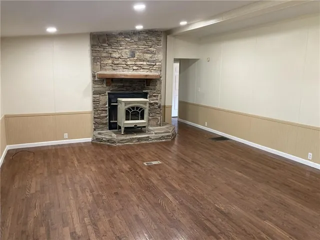 an empty room with wooden floor a fireplace and windows