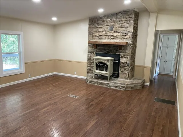 an empty room with wooden floor fireplace and windows