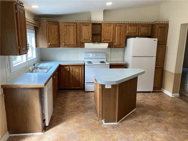 a kitchen with granite countertop a sink a stove and refrigerator