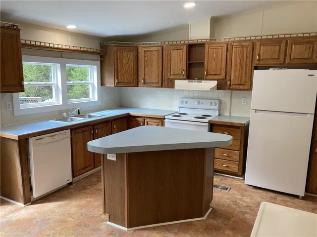 a kitchen with kitchen island a sink a stove and a refrigerator