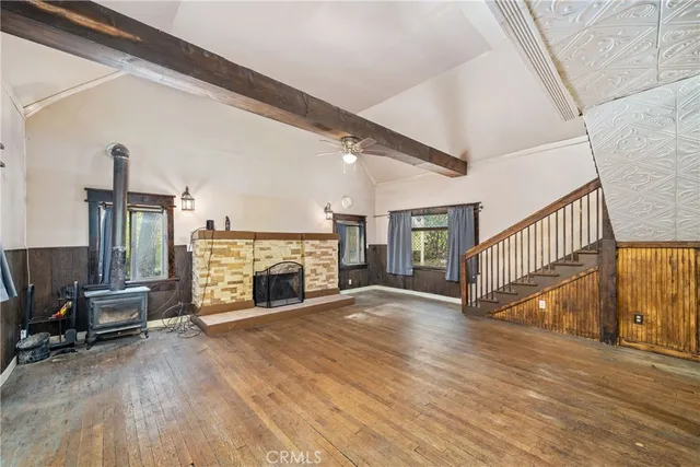 a view of an empty room with wooden floor fireplace and a window