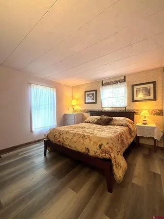 a bedroom with a bed wooden floor and window