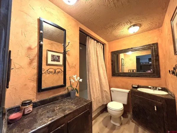 a bathroom with a granite countertop toilet sink and mirror