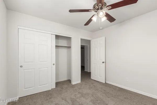 an empty room with closet and a chandelier fan
