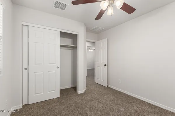 an empty room with a ceiling fan and carpet