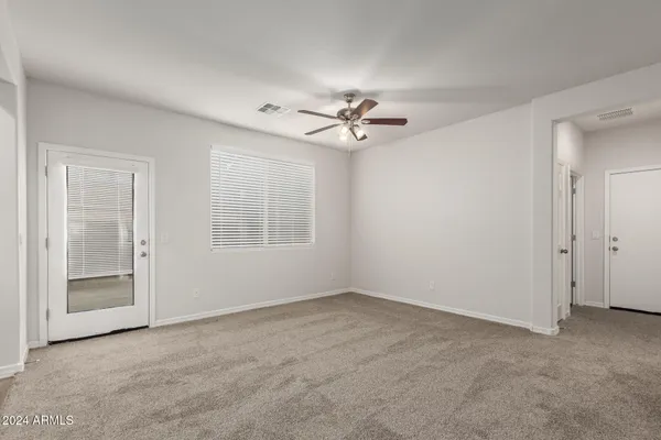 an empty room with chandelier fan and windows