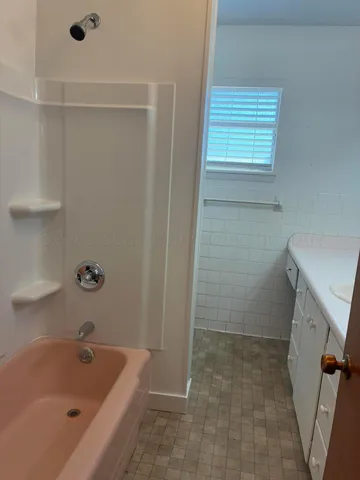 a bathroom with a tub a sink and a window