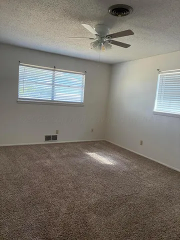 an empty room with a ceiling fan and window