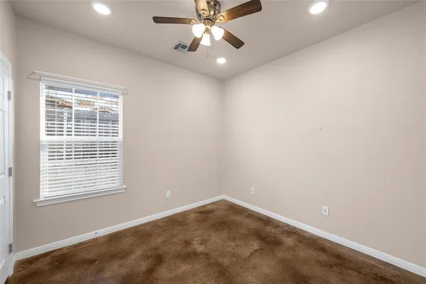 an empty room with a window and a fan