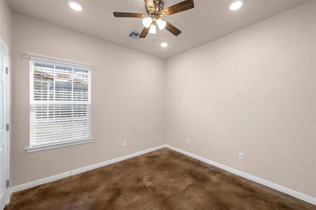 an empty room with a window and a fan