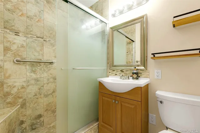 a bathroom with a sink a toilet a mirror and shower