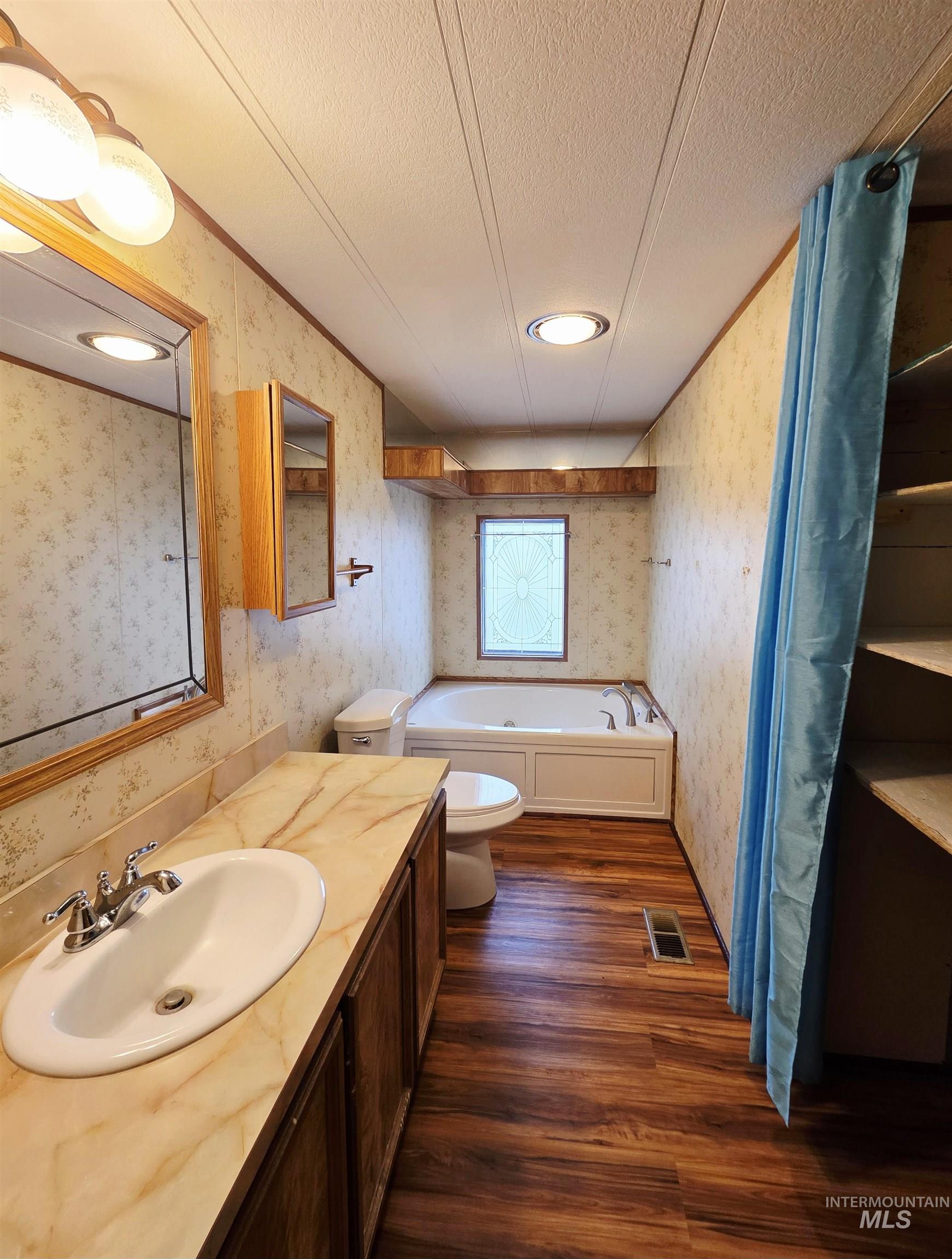 2015 6th Avenue, Unit 14 Clarkston, WA 99403 - Photo 19 of 27 Bathroom with dark wood-style flooring, a garden tub, vanity, a textured ceiling, and crown molding