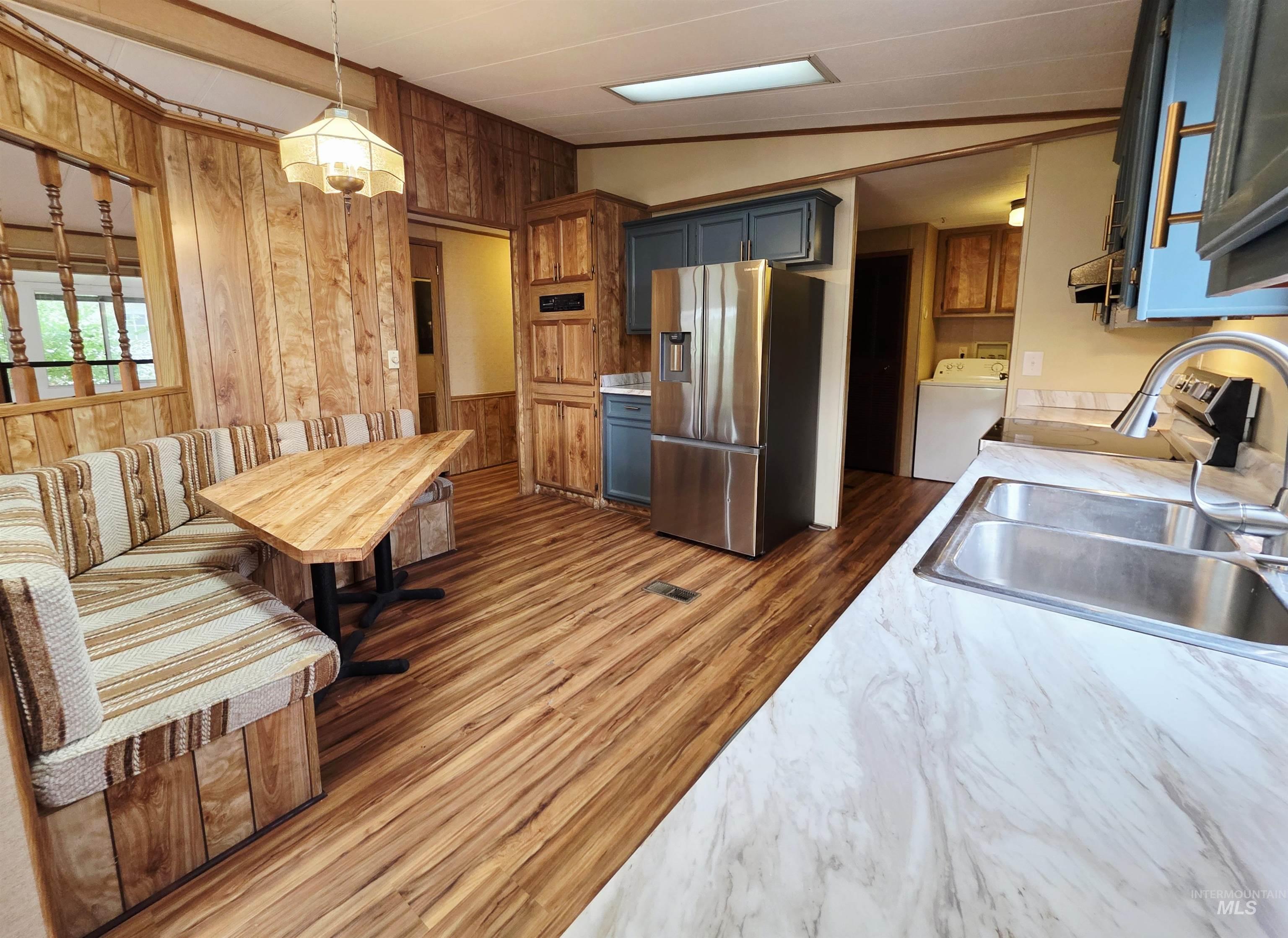 2015 6th Avenue, Unit 14 Clarkston, WA 99403 - Photo 6 of 27 Kitchen with wooden walls, stainless steel fridge with ice dispenser, light countertops, hanging light fixtures, and washer / dryer
