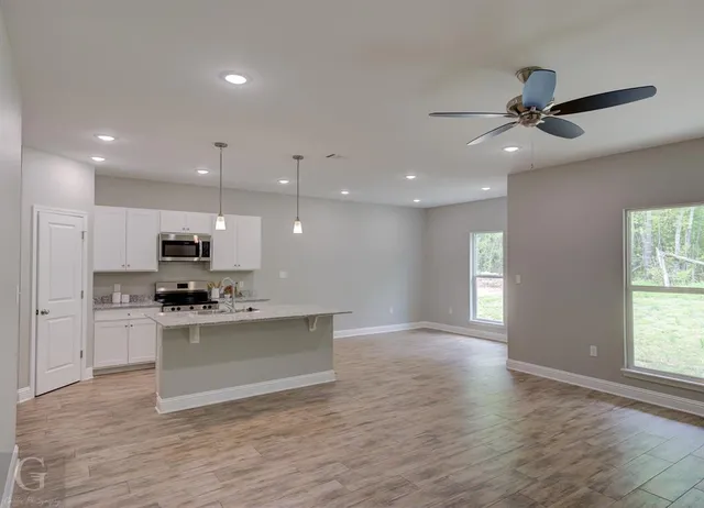 a kitchen with kitchen island granite countertop a sink a counter space appliances and cabinets