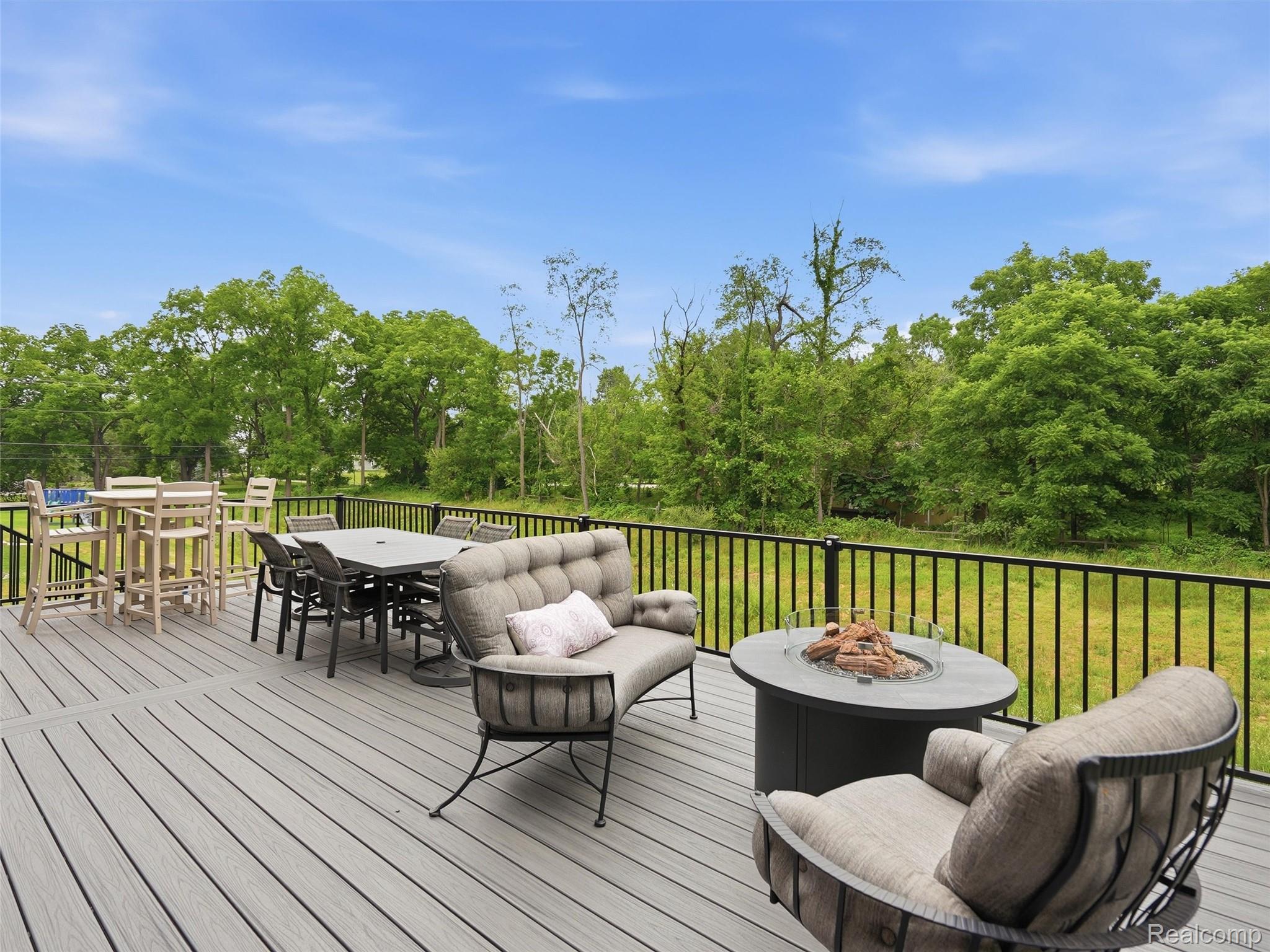 3007 28 Mile Road Washington, MI 48094 - Photo 52 of 69 Expansive outdoor deck featuring composite decking, black metal railings, and a built-in fire pit