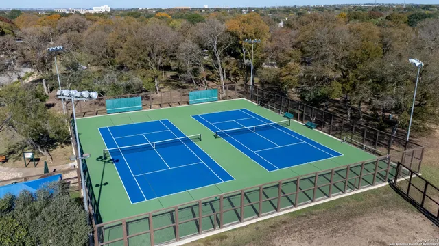 a view of a tennis ground with large trees