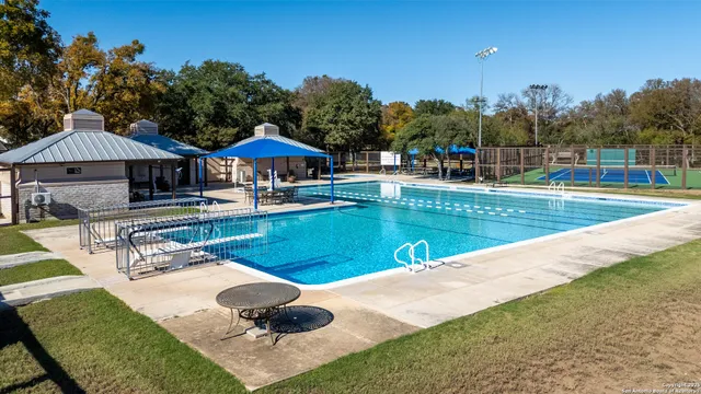 a view of a swimming pool with a table and chairs under an umbrella
