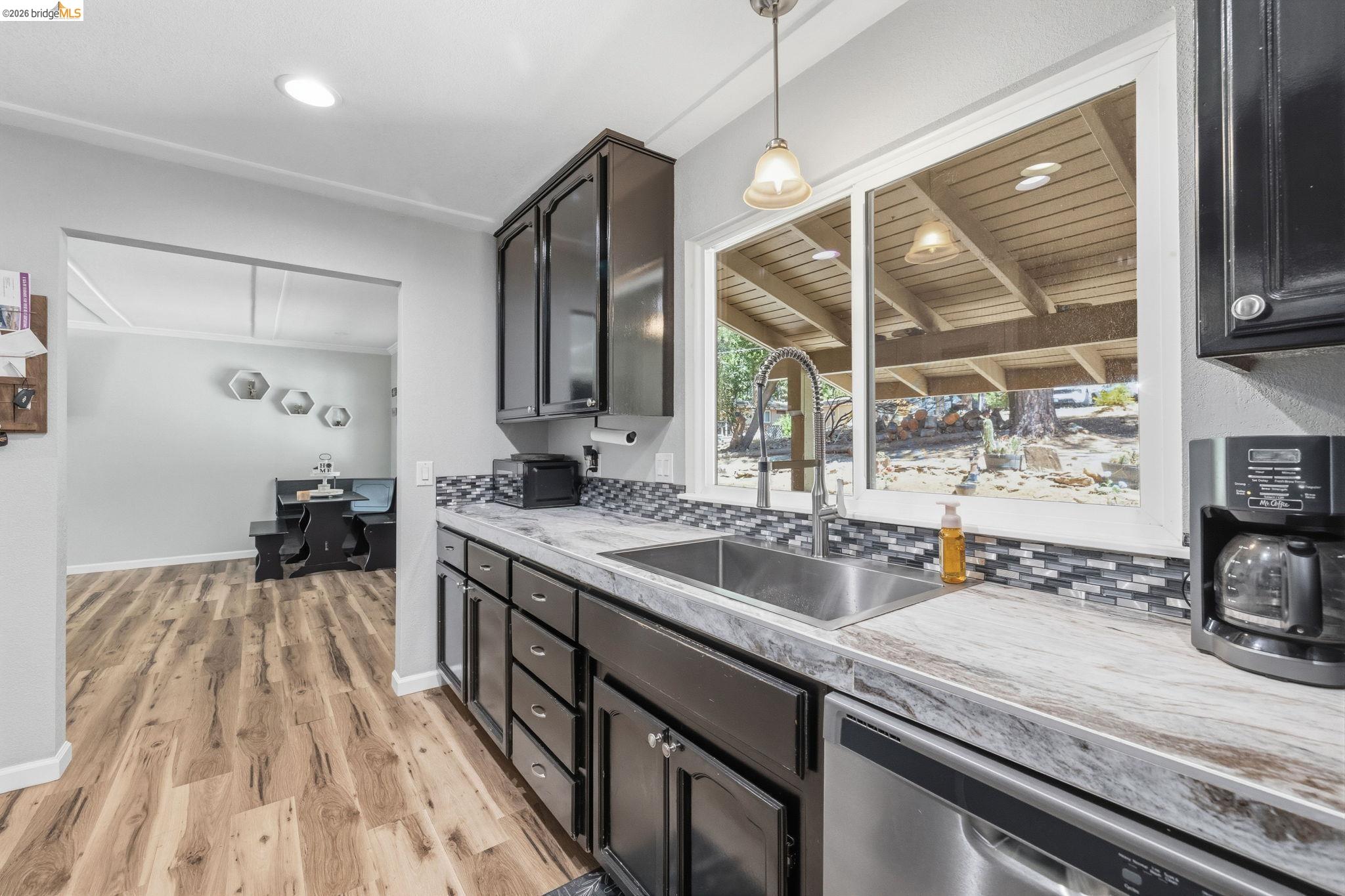 19059 Raboul Court Groveland, CA 95321 - Photo 10 of 21 Kitchen area featuring wood-finish flooring, dark cabinetry, and a mosaic tile backsplash
