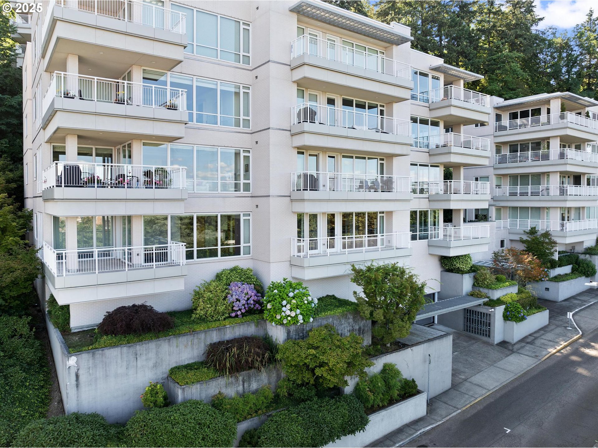 a front view of a building with balcony and garden