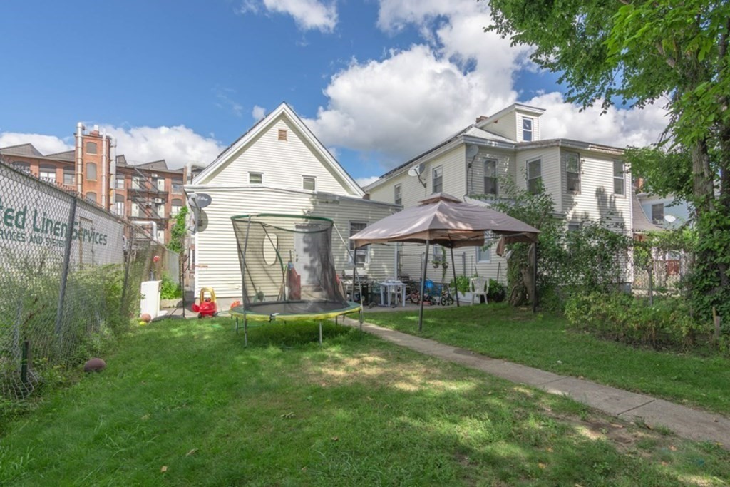 58 Lake Street Lawrence, MA 01841 - Photo 26 of 26 a view of a white house with a yard and table and chairs under an umbrella