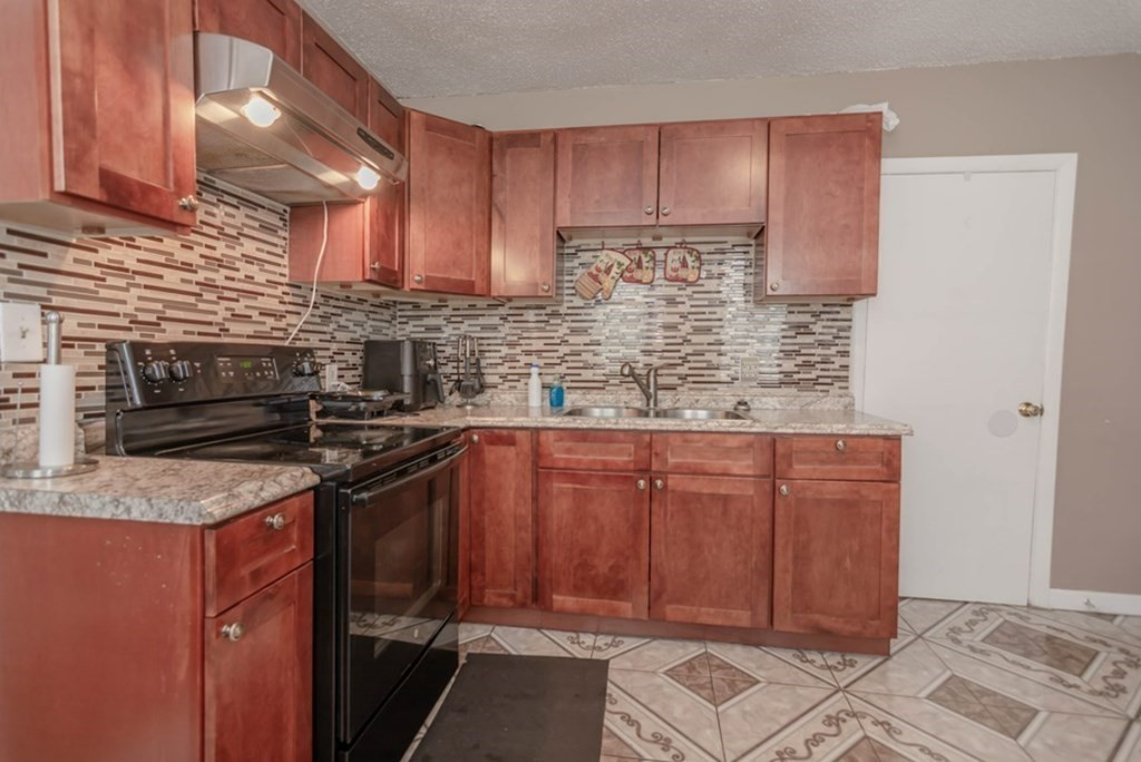 58 Lake Street Lawrence, MA 01841 - Photo 10 of 26 a kitchen with stainless steel appliances granite countertop a sink stove and cabinets